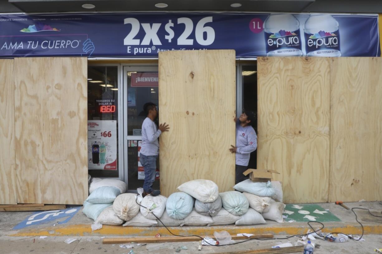 FILE - Workers board up a grocery store to protect it from Hurricane Milton, in Progreso, Yucatan state, Mexico, Oct. 7, 2024.