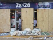 FILE - Workers board up a grocery store to protect it from Hurricane Milton, in Progreso, Yucatan state, Mexico, Oct. 7, 2024.