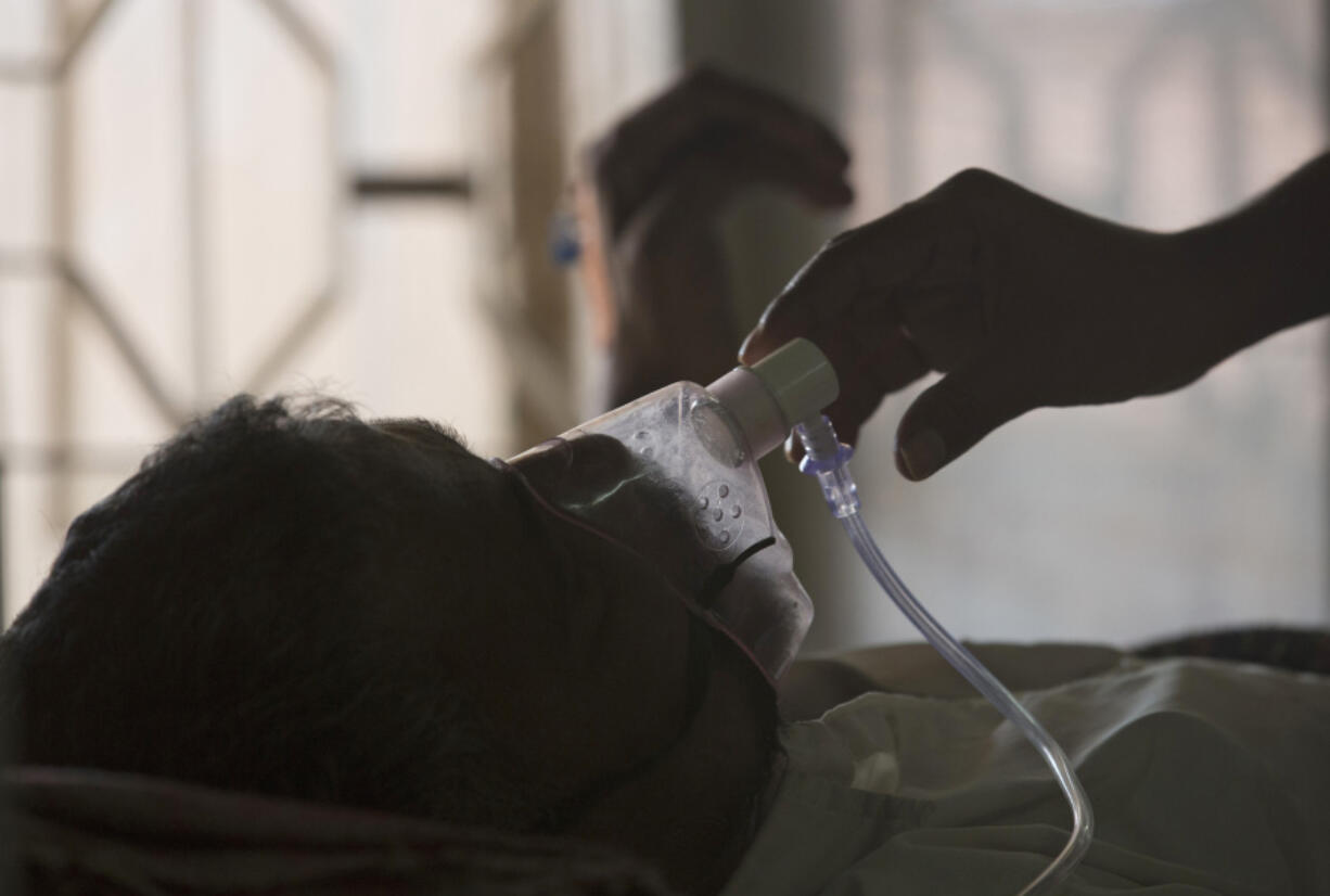 FILE - A relative adjusts the oxygen mask of a tuberculosis patient at a TB hospital on World Tuberculosis Day in Hyderabad, India, March 24, 2018.