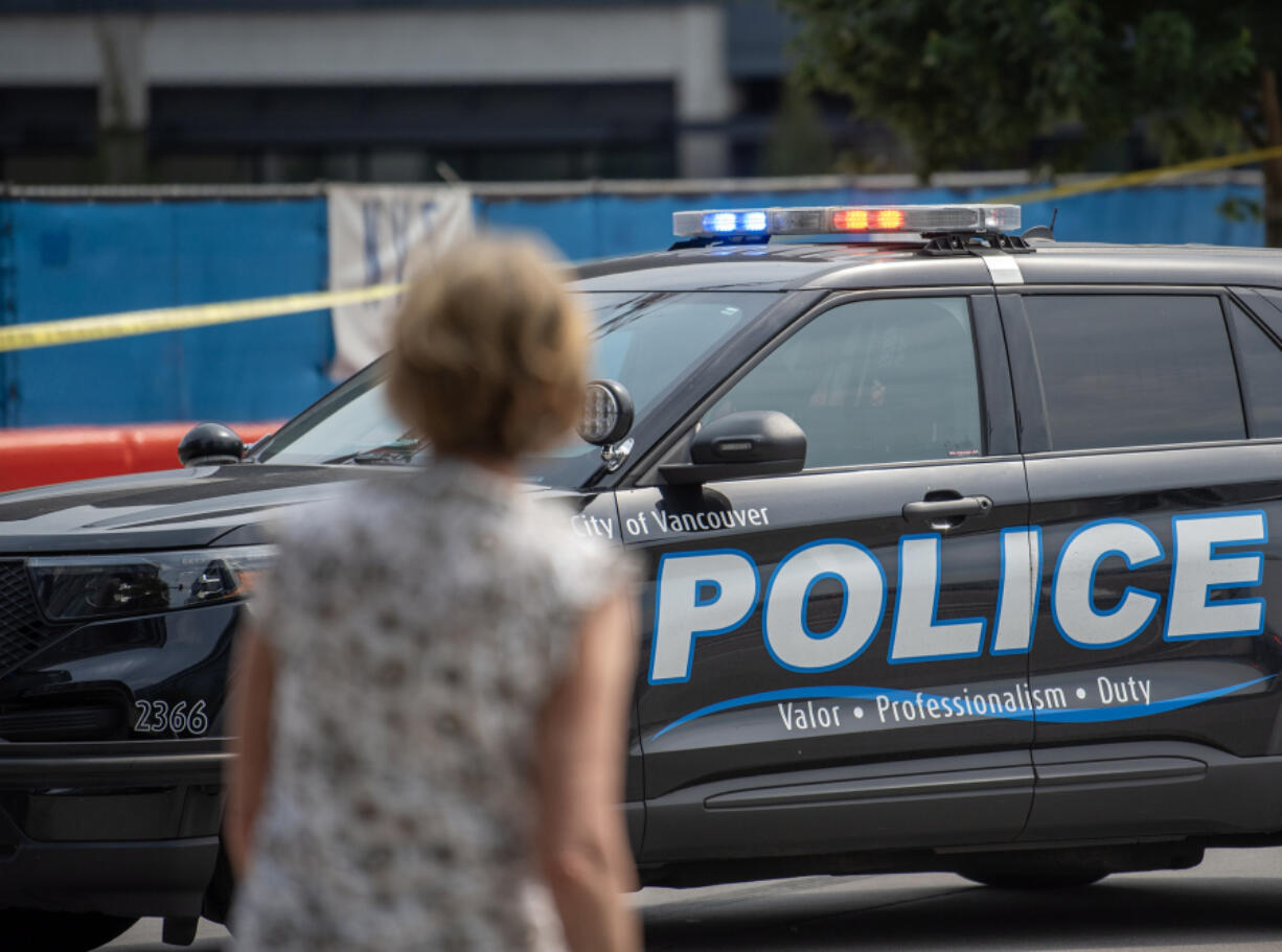 A pedestrian looks at a Vancouver Police car blocking the intersection of Esther Street and West Columbia Way on Aug. 9 in Vancouver.