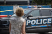 A pedestrian looks at a Vancouver Police car blocking the intersection of Esther Street and West Columbia Way on Aug. 9 in Vancouver.