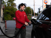 Brandon Borg, 21, fills up his car with gas in Everett, Oct. 24, 2024. Borg must drive long distances for work and is worried about how the rise in gas prices will affect his ability to save money for his future.