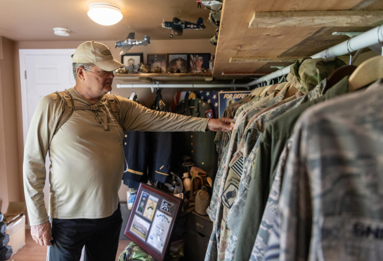 Thomas Renner Sr., 72, flips through his collection of military uniforms at his home in Woodland. At 18, he volunteered to fight in the Vietnam War. He has 32 family members who have served, including his son, Josiah Renner.  At top, Thomas Renner Sr., right, during the Vietnam War.