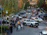 Law enforcement officers are seen as people wait to register to vote, left, and drop off their ballots at the downtown Vancouver elections office Monday evening, Nov. 4, 2024.