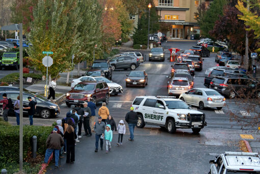 Law enforcement officers are seen as people wait to register to vote, left, and drop off their ballots at the downtown Vancouver elections office Monday evening, Nov. 4, 2024.