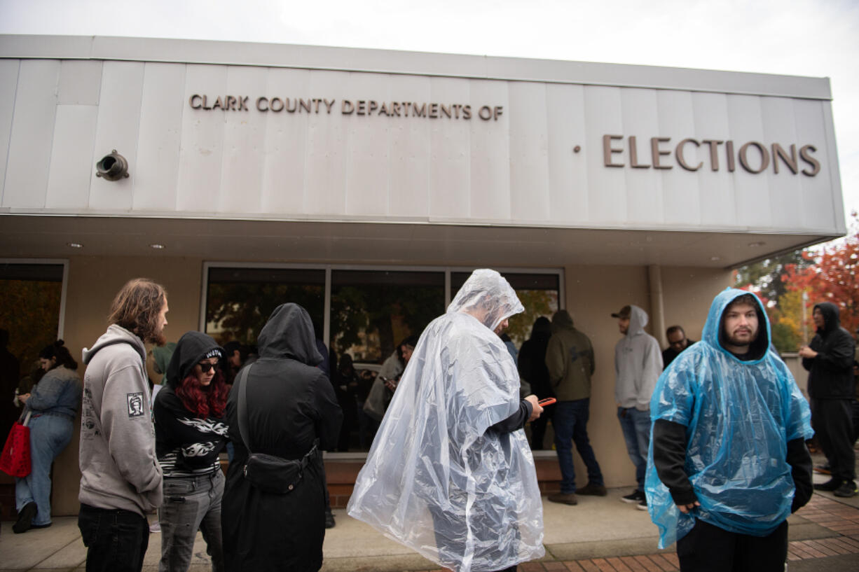 Local residents attempt to stay dry as wait at the Clark County Elections Office in downtown Vancouver on Tuesday afternoon.