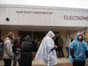 Local residents attempt to stay dry as wait at the Clark County Elections Office in downtown Vancouver on Tuesday afternoon.