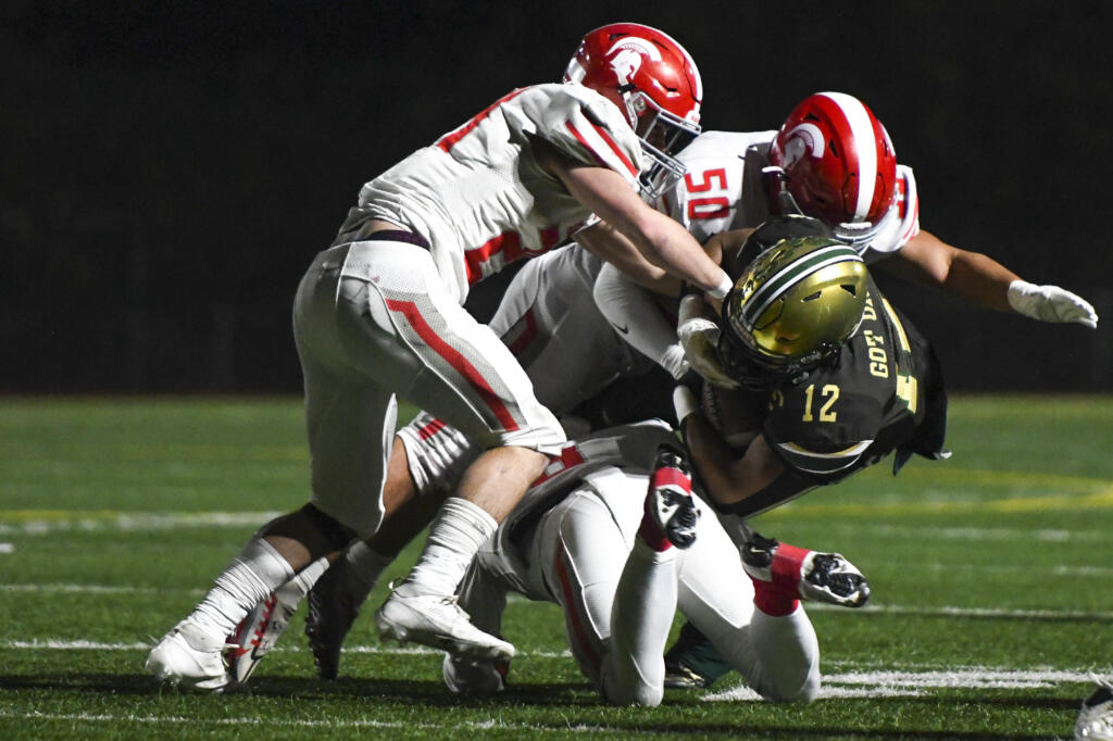 Evergreen running back James Bethune (12) is tackled by a group of Stanwood defenders during the first quarter of a 3A Washington State preliminary playoff football game at McKenzie Stadium in Vancouver, Wash., on Friday, Nov. 8, 2024.