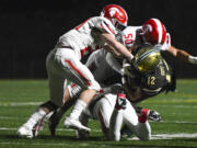 Evergreen running back James Bethune (12) is tackled by a group of Stanwood defenders during the first quarter of a 3A Washington State preliminary playoff football game at McKenzie Stadium in Vancouver, Wash., on Friday, Nov. 8, 2024.