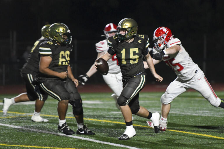 Evergreen quarterback Jayden Baum (15) escapes pressure from Stanwood defensive lineman Trey VanPutten (77) during the fourth quarter of a 3A Washington State preliminary playoff football game at McKenzie Stadium in Vancouver, Wash., on Friday, Nov. 8, 2024.