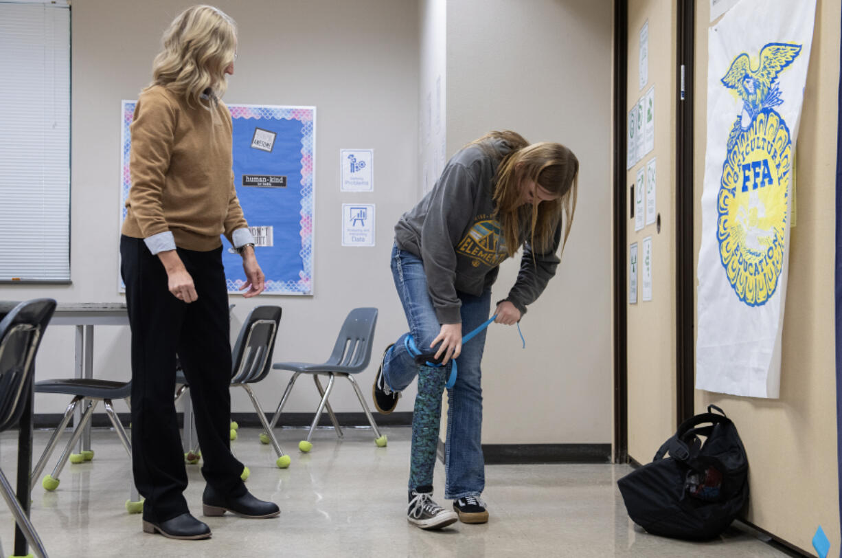 Science teacher Jill Cole, left, looks on as junior Bailey Fling, 16, tries out the prosthetic leg she created during her careers in science class at La Center High School on Thursday morning.