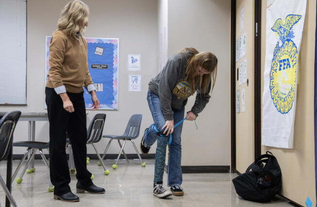 Science teacher Jill Cole, left, looks on as junior Bailey Fling, 16, tries out the prosthetic leg she created during her careers in science class at La Center High School on Thursday morning.