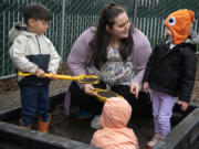 St. Johns Early Learning Center student Kani Dando, 4, from left, plays in a sandbox Monday with teacher-in-training Tia Thomas and student Daria Shenderovska, also 4. Thomas went through Educational Opportunities for Children and Families&rsquo; Parent University to work in early education.