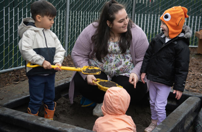 St. Johns Early Learning Center student Kani Dando, 4, from left, plays in a sandbox Monday with teacher-in-training Tia Thomas and student Daria Shenderovska, also 4. Thomas went through Educational Opportunities for Children and Families&rsquo; Parent University to work in early education.