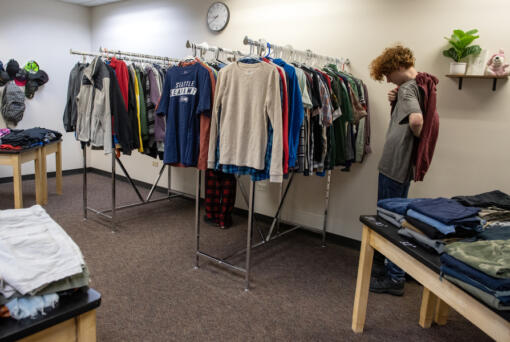 Junior Mathias Darnielle, 16, tries on a hooded sweatshirt while stopping by the BG Thrift Store on Wednesday at Battle Ground High School.