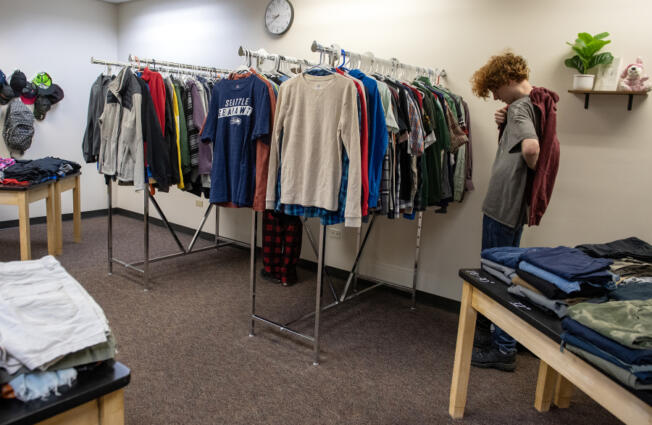 Junior Mathias Darnielle, 16, tries on a hooded sweatshirt while stopping by the BG Thrift Store on Wednesday at Battle Ground High School.