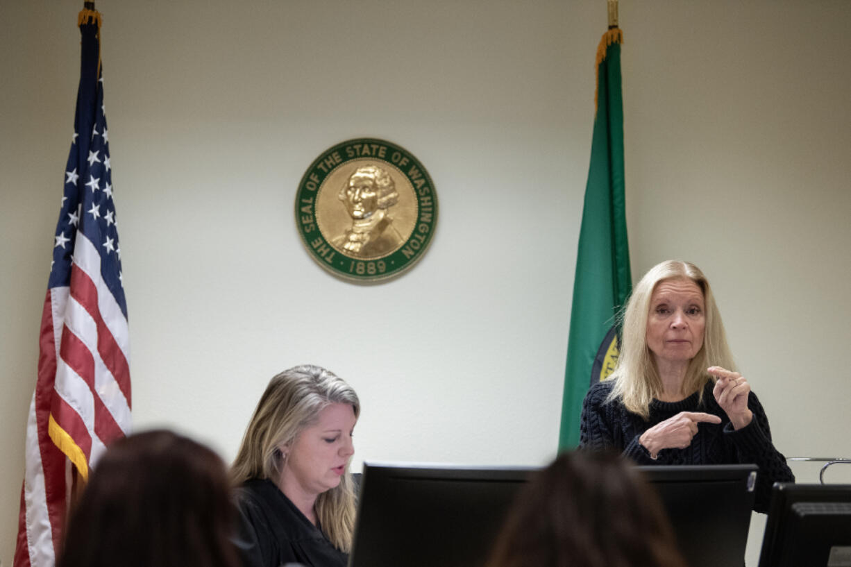 Clark County Superior Court Commissioner Jill Sasser, left, signs a court order while Luanne Conner interprets the commissioner&rsquo;s ruling into American Sign Language on Nov. 21 for a party in a hearing at the county&rsquo;s Family Law Annex. Conner is one of more than 100 interpreters the local justice system has used this year.