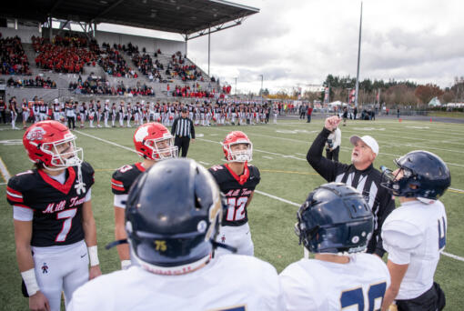 Camas, left, and Arlington captains watch the coin toss before a Class 4A state quarterfinal playoff game at Doc Harris Stadium in Camas on Saturday.