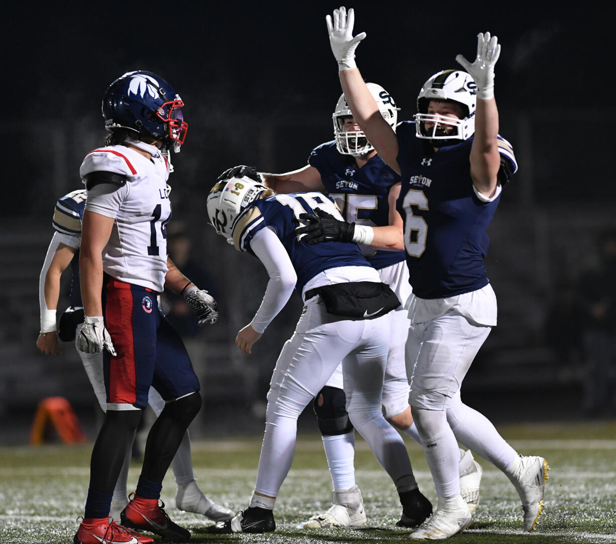 Seton players celebrate with sophomore Conner Selby (14) after Selby make the game-winning extra point Saturday, Nov. 23, 2024, during the Cougars’ 42-41 win against Life Christian Academy in the 1A State Football Playoff quarterfinals at Doc Harris Stadium in Camas.