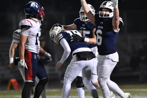 Seton players celebrate with sophomore Conner Selby (14) after Selby make the game-winning extra point Saturday, Nov. 23, 2024, during the Cougars’ 42-41 win against Life Christian Academy in the 1A State Football Playoff quarterfinals at Doc Harris Stadium in Camas.