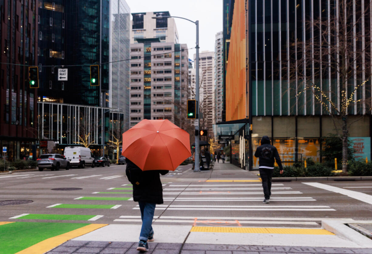 A person walks near Amazon office buildings near 7th Avenue and Blanchard Street on Jan. 17, 2023, in Seattle.