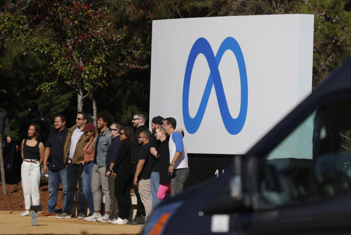 Facebook employees gather in front of a sign displaying a new logo and the name &lsquo;Meta&rsquo; in front of Facebook headquarters on Oct. 28, 2021, in Menlo Park, Calif.