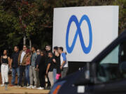 Facebook employees gather in front of a sign displaying a new logo and the name &lsquo;Meta&rsquo; in front of Facebook headquarters on Oct. 28, 2021, in Menlo Park, Calif.