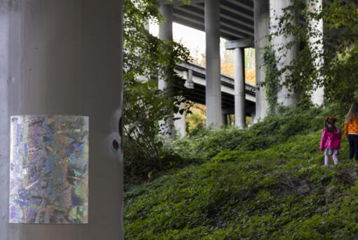 Two girls walk past one of artist Matthew Offenbacher&rsquo;s seven pieces of art on display on a column under Interstate 5 at Colonnade Park in Seattle on Oct. 24. (Photos by Ellen M.