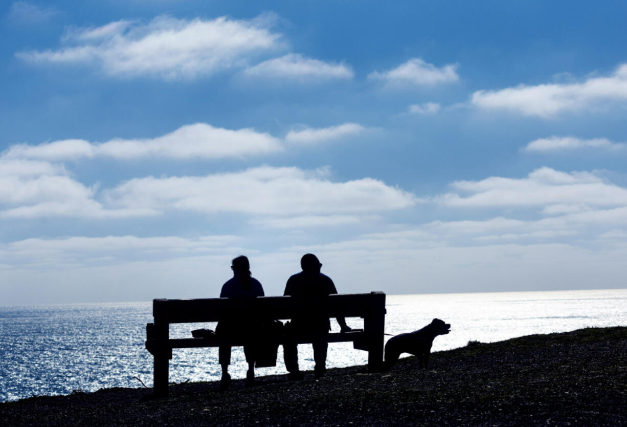 The first day of spring provided a sunny bench for a pair of hikers and their dog at Mori Point, March 19, 2024, in Pacifica, California.