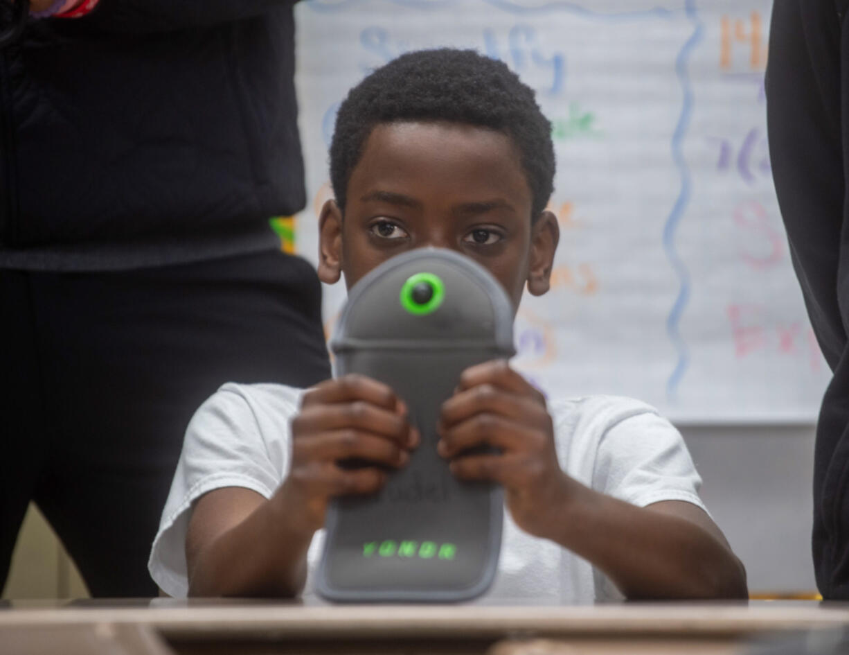 Seventh grader Kwasi Noumedor 12, holds a Yondr Pouch, which students can lock their phones during the day during school.