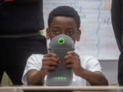 Seventh grader Kwasi Noumedor 12, holds a Yondr Pouch, which students can lock their phones during the day during school.