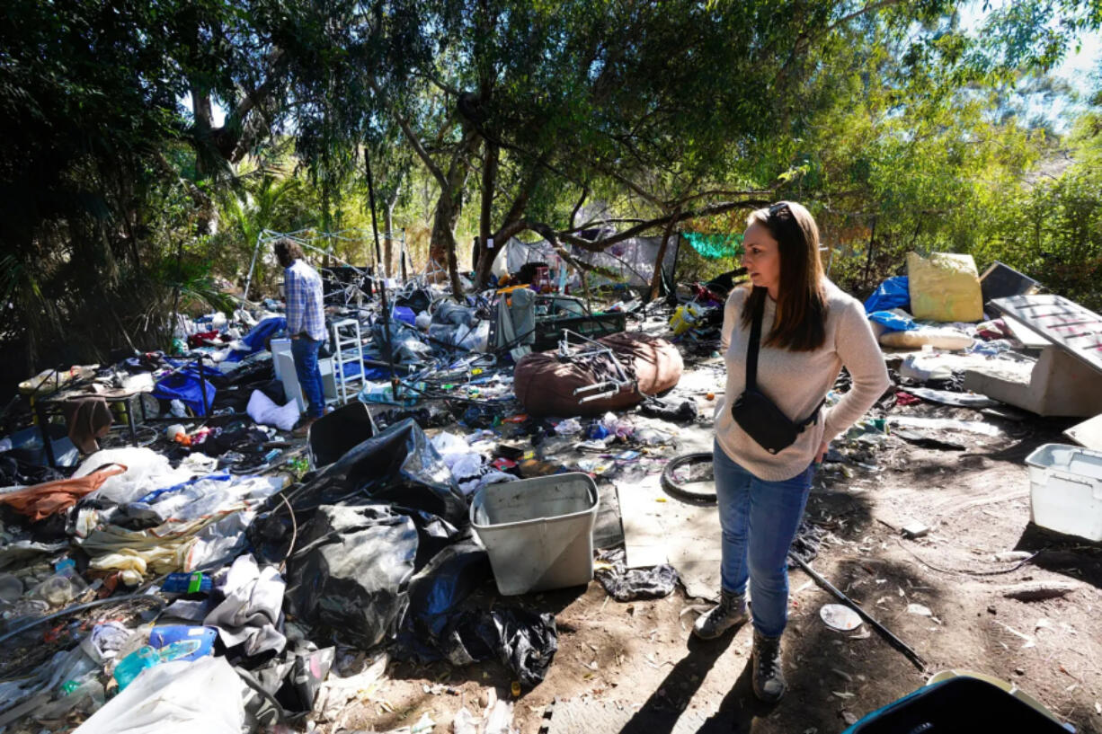 On Thursday, Nov. 7, 2024, in San Diego, Shelly Stewart and Jason Stewart walk about their property that ends near the Interstate 15 freeway. Hidden from sight by large trees and shrubs, the couple learned recently of a large and dense encampment located at the very back of their property. (Nelvin C.