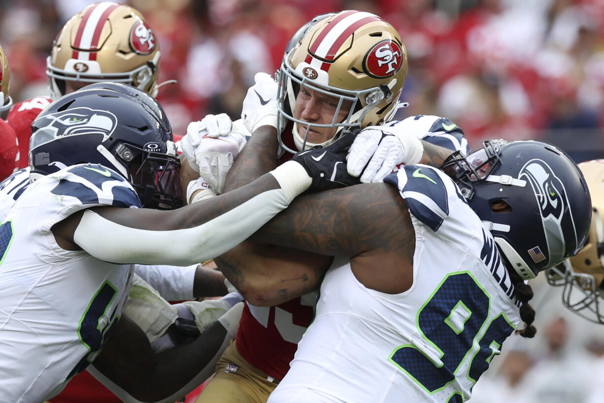 San Francisco 49ers running back Christian McCaffrey, middle, runs against Seattle Seahawks linebacker Tyrice Knight, foreground left, linebacker Ernest Jones IV, left rear, defensive tackle Byron Murphy II, rear, and defensive end Leonard Williams during the first half of an NFL football game in Santa Clara, Calif., Sunday, Nov. 17, 2024.