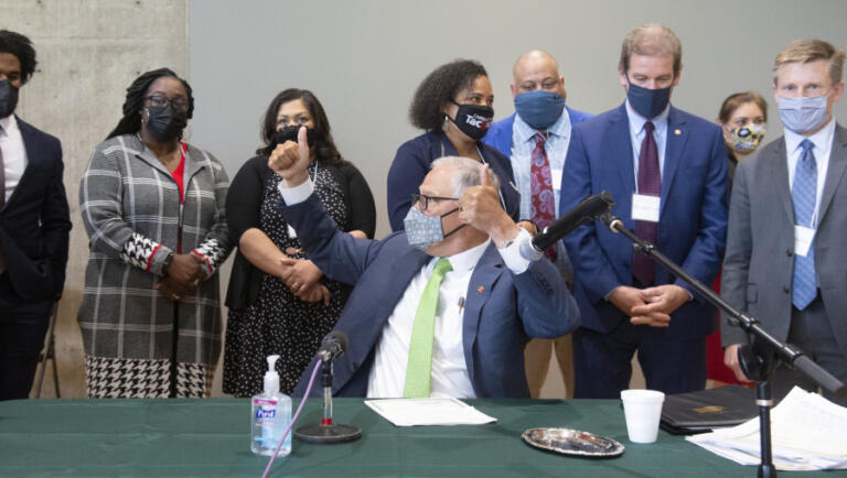 Washington Gov. Jay Inslee throws two thumbs up after completing the signing of 12 bills about police accountability during ceremonies at the Eastside Community Center in Tacoma, Wash., on Tuesday, May 18, 2021.