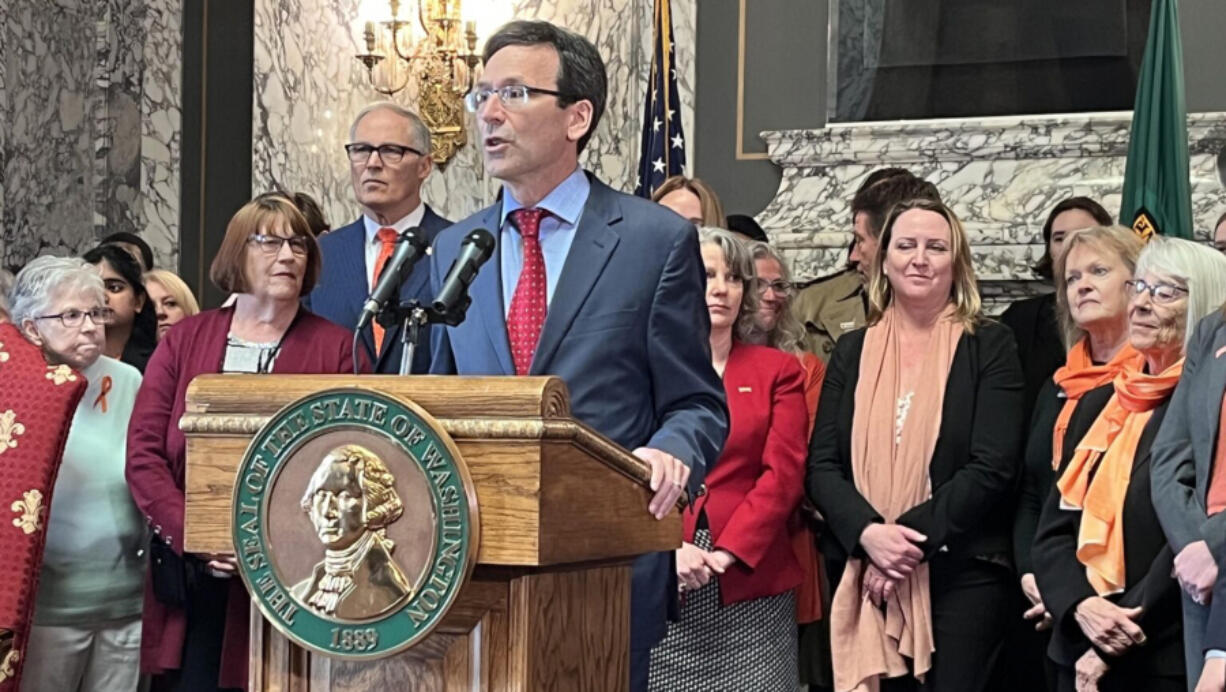 Washington state Attorney General Bob Ferguson (at podium) makes remarks prior to Gov. Jay Inslee (to the left of Ferguson) signing a package of gun legislation in April 2023.