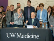 Washington Gov. Jay Inslee (seated) prepares to sign the 2024 supplemental budget on March 29, 2024. He was joined by several Democratic state lawmakers, including, to his right, Sen. June Robinson, the lead Senate budget writer.