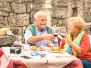 An empty-nester couple enjoys a meal at a restaurant while on vacation. New research found that two-fifths (41 percent) of American parents would rather spend money on a trip of a lifetime in 2025 than leaving inheritance to their children.