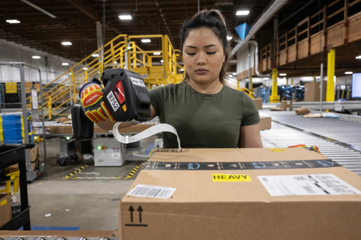 Juliet Dusuntia marks inbound packages before they are sent down a conveyor belt at the Amazon delivery station in Anchorage, Alaska, on Nov. 12, 2024.