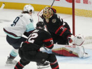 Ottawa Senators goaltender Anton Forsberg makes a save on Seattle Kraken left wing Jared McCann as Senators defenseman Thomas Chabot defends during the third period of an NHL hockey game, Saturday, Nov. 2, 2024, in Ottawa.