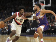 Portland Trail Blazers guard Scoot Henderson (00) drives against Phoenix Suns guard Tyus Jones, right, during the first half of an NBA basketball game, Saturday, Nov. 2, 2024, in Phoenix.