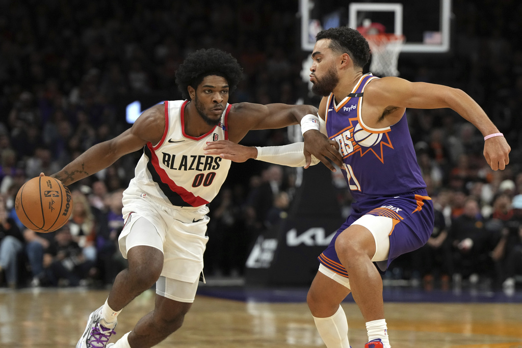 Portland Trail Blazers guard Scoot Henderson (00) drives against Phoenix Suns guard Tyus Jones, right, during the first half of an NBA basketball game, Saturday, Nov. 2, 2024, in Phoenix.