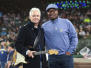 Pearl Jam guitarist Mike McCready, left, and Mariners broadcaster Dave Sims pose for a photo before McCready performs the national anthem at a baseball game between the Seattle Mariners and the Los Angeles Angels, Sunday, June 2, 2024, in Seattle. Sims is now going to be a play-by-play announcer for the New York Yankees.