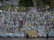 People walk past the memorial to fallen soldiers in Independence Square in Kyiv, Ukraine, Friday, Nov. 15, 2024.