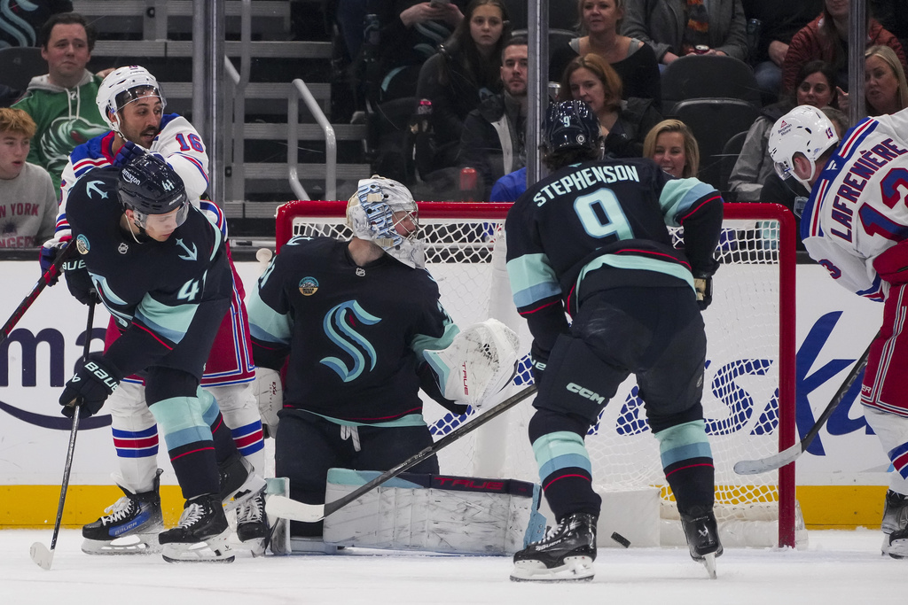 New York Rangers left wing Alexis Lafrenière (13) scores against Seattle Kraken goaltender Philipp Grubauer as center Chandler Stephenson (9), defenseman Ryker Evans (41) and Rangers center Vincent Trocheck (16) look on during the second period of an NHL hockey game Sunday, Nov. 17, 2024, in Seattle.