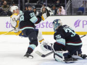 Nashville Predators center Juuso Parssinen (13) is hit by Seattle Kraken defenseman Joshua Mahura (28) in front of the goal during the second period of an NHL hockey game, Wednesday, Nov. 20, 2024, in Seattle.