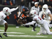 Washington State defensive backs Stephen Hall (1) and Tanner Moku (32) tackle Oregon State running back Salahadin Allah (26) during the first half of an NCAA college football game Saturday, Nov. 23, 2024, in Corvallis, Ore.