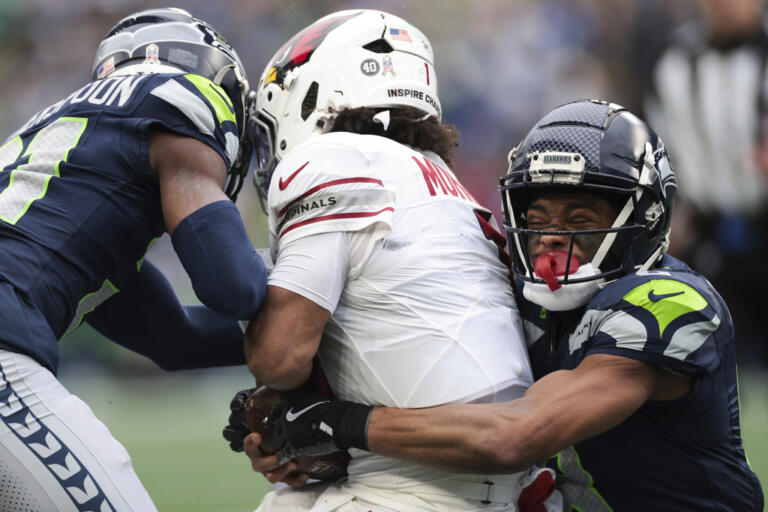 Seattle Seahawks cornerback Devon Witherspoon, left, and cornerback Coby Bryant, right, tackle Arizona Cardinals quarterback Kyler Murray during the first half of an NFL football game Sunday, Nov. 24, 2024, in Seattle.