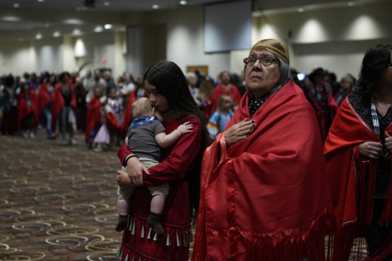 Confederated Tribes of Siletz Indians member Ramona Hudson, of Aumsville, Ore., right, looks up as her cousin Aurora Chulik-Ruff, 12, holds her five-month-old brother Bear Chulik-Moore, as they walk during a dance dedicated to missing and murdered indigenous women during a powwow at Chinook Winds Casino Resort, Saturday, Nov. 16, 2024, in Lincoln City, Ore.