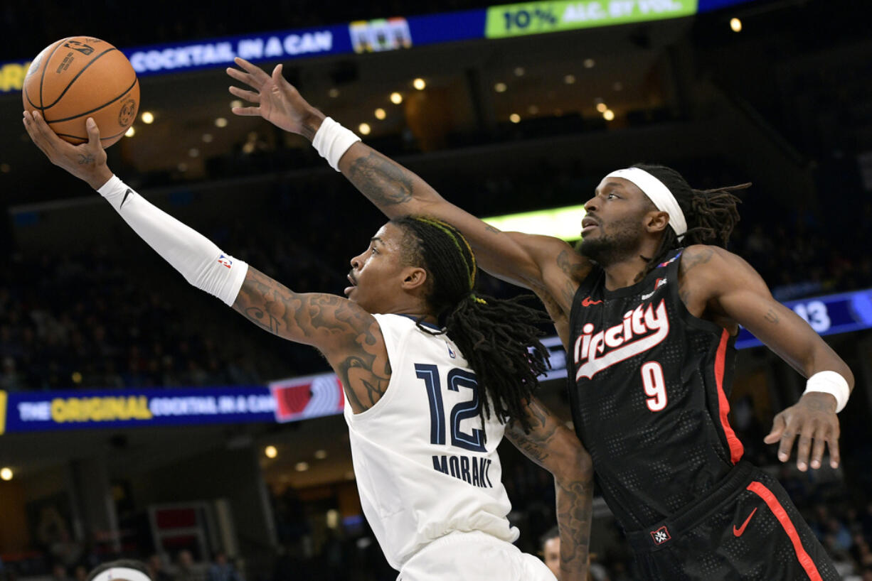 Memphis Grizzlies guard Ja Morant (12) shows ahead of Portland Trail Blazers forward Jerami Grant (9) in the first half of an NBA basketball game Monday, Nov. 25, 2024, in Memphis, Tenn.