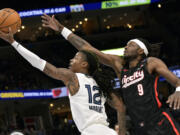 Memphis Grizzlies guard Ja Morant (12) shows ahead of Portland Trail Blazers forward Jerami Grant (9) in the first half of an NBA basketball game Monday, Nov. 25, 2024, in Memphis, Tenn.